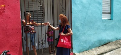 Mujeres saludándose a través de reja de una casa 